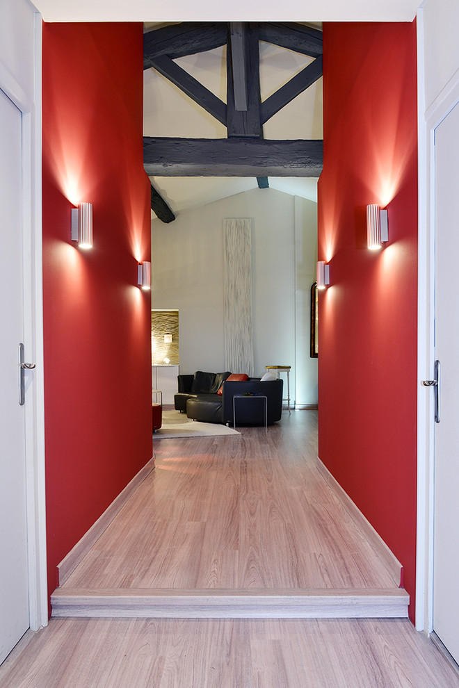 Exemple d'un couloir tendance de taille moyenne avec un mur rouge, parquet clair et un sol beige.