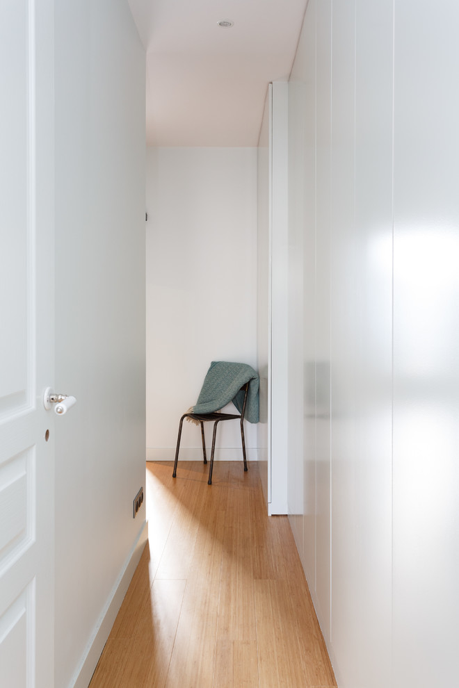 Aménagement d'un petit couloir moderne avec un mur blanc, un sol en bois brun et un sol marron.