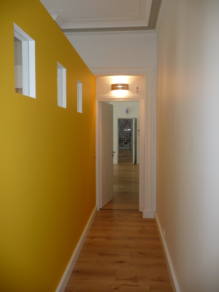 На фото: огромный коридор в стиле модернизм с желтыми стенами и светлым паркетным полом