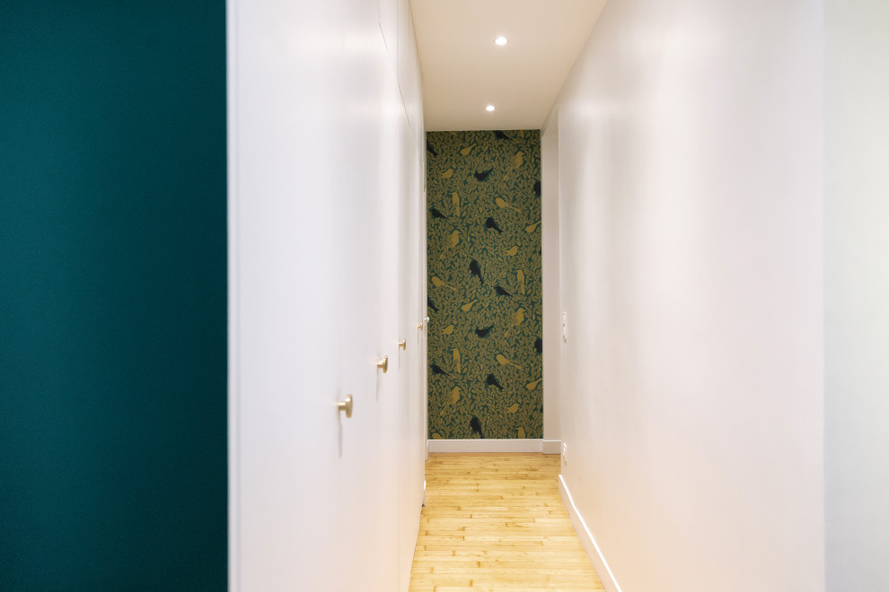 Idée de décoration pour un couloir minimaliste de taille moyenne avec un mur blanc, parquet clair et un sol beige.