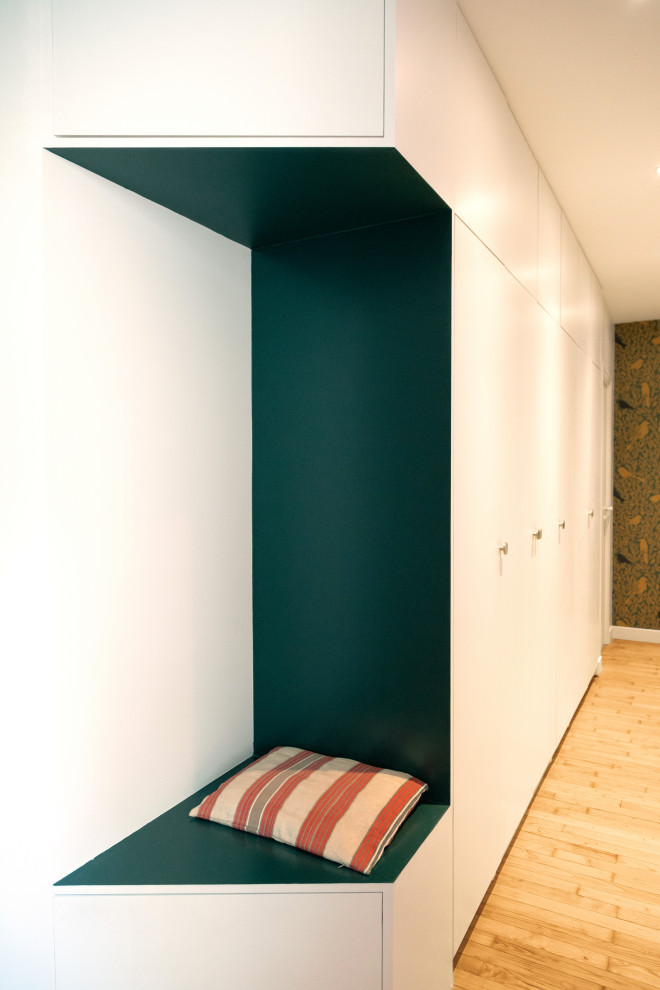 Modern inredning av en mellanstor hall, med vita väggar, ljust trägolv och beiget golv