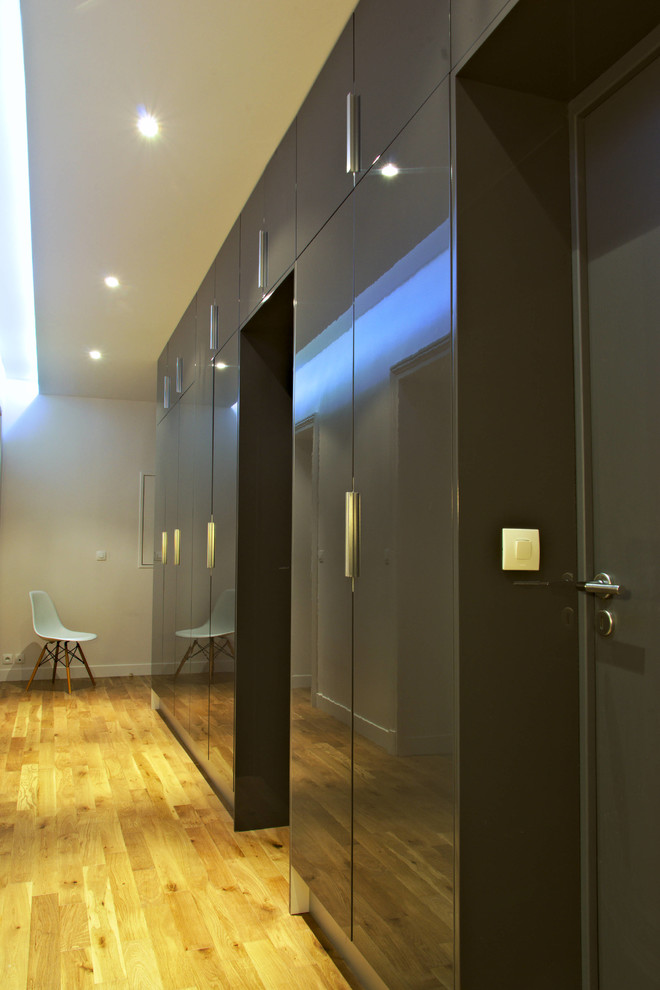 Idée de décoration pour un couloir design de taille moyenne avec un mur blanc, parquet clair et un sol beige.