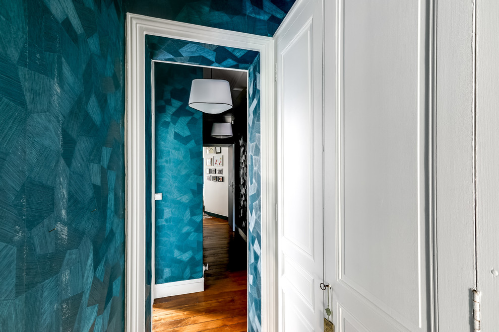 Inredning av en modern mellanstor hall, med blå väggar, ljust trägolv och beiget golv