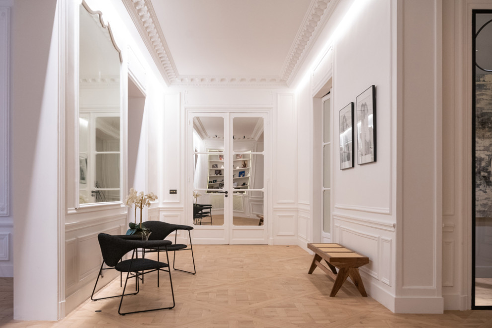 Réalisation d'un grand couloir design avec un mur blanc, parquet clair et un sol beige.