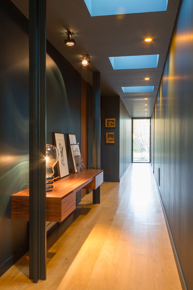 Exemple d'un grand couloir tendance avec un mur bleu et un sol en bois brun.