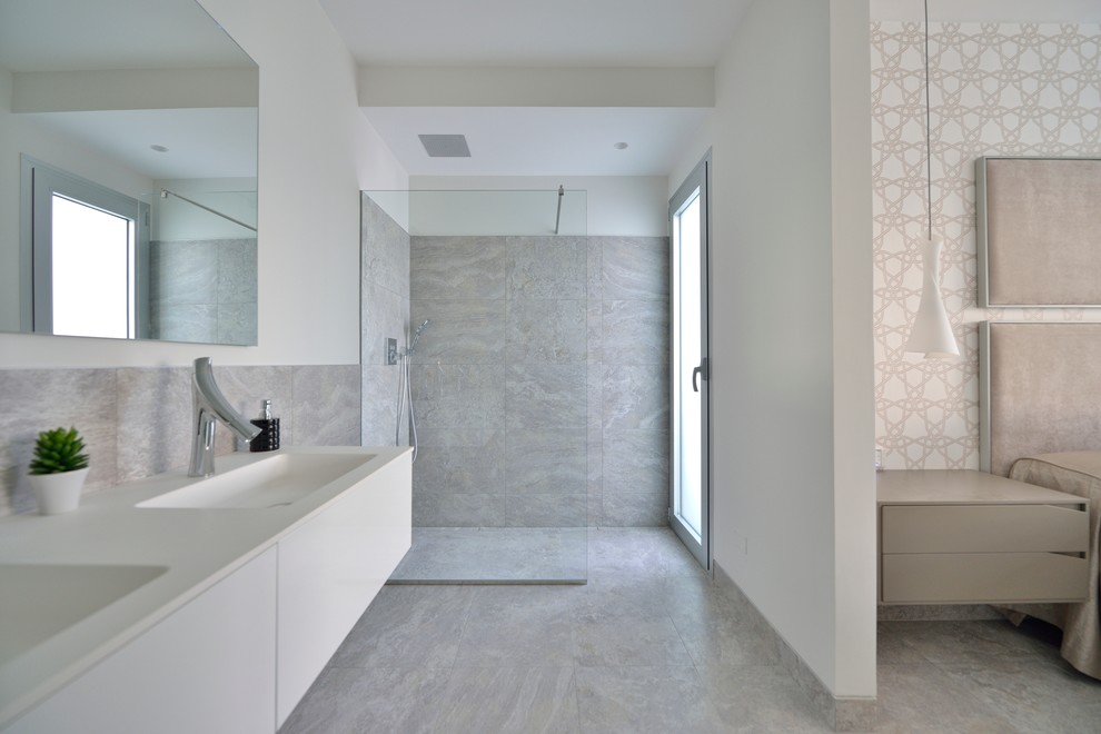 Immagine di una stanza da bagno con doccia mediterranea di medie dimensioni con ante lisce, ante bianche, doccia a filo pavimento, pareti bianche e lavabo integrato
