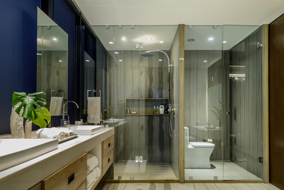 Contemporary ensuite bathroom in Mexico City with grey tiles, marble tiles, grey walls, marble flooring, marble worktops, flat-panel cabinets, medium wood cabinets, an alcove shower, a built-in sink, grey floors and a hinged door.