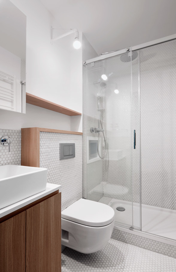 Foto de cuarto de baño escandinavo de tamaño medio con armarios con paneles lisos, puertas de armario de madera oscura, ducha empotrada, sanitario de pared, paredes blancas, aseo y ducha y lavabo sobreencimera