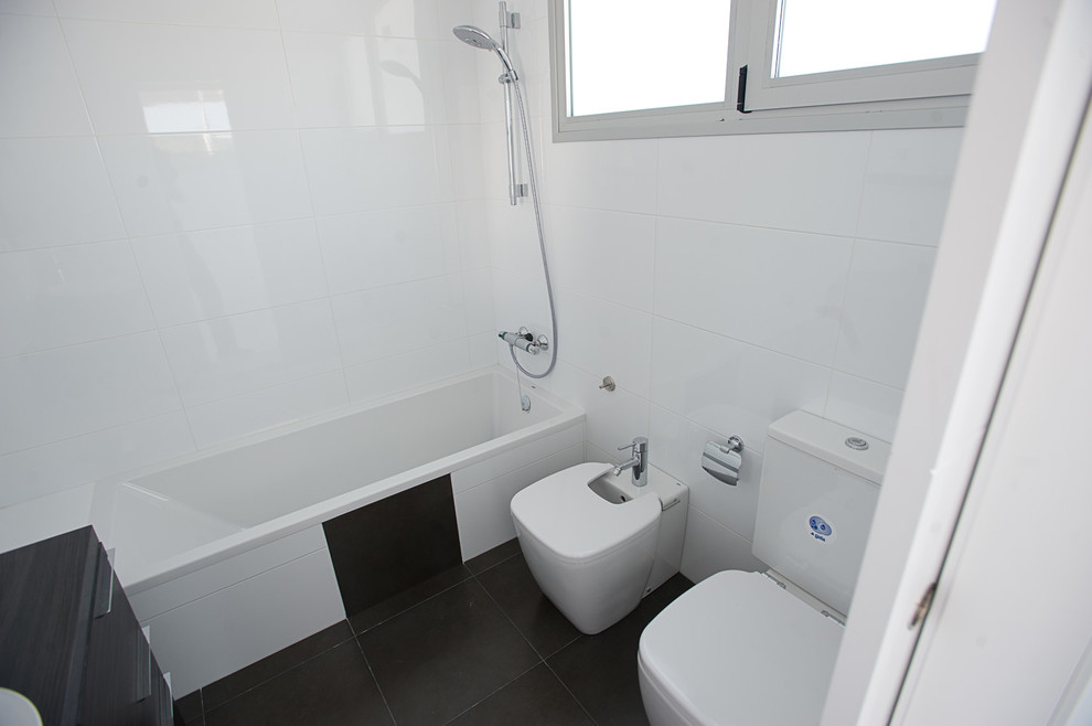 Пример оригинального дизайна: маленькая главная ванная комната в современном стиле с ванной в нише, душем над ванной, биде, белыми стенами, полом из керамической плитки и накладной раковиной для на участке и в саду