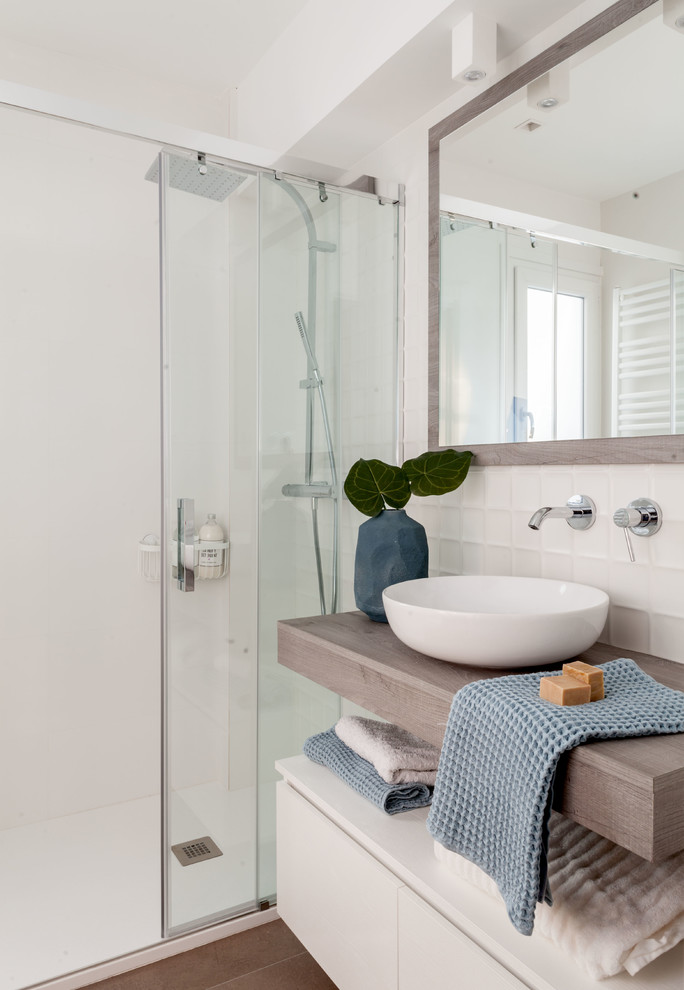 Design ideas for a contemporary bathroom in Bilbao with flat-panel cabinets, white cabinets, an alcove shower, white walls, a vessel sink, wooden worktops, brown floors, a sliding door and brown worktops.