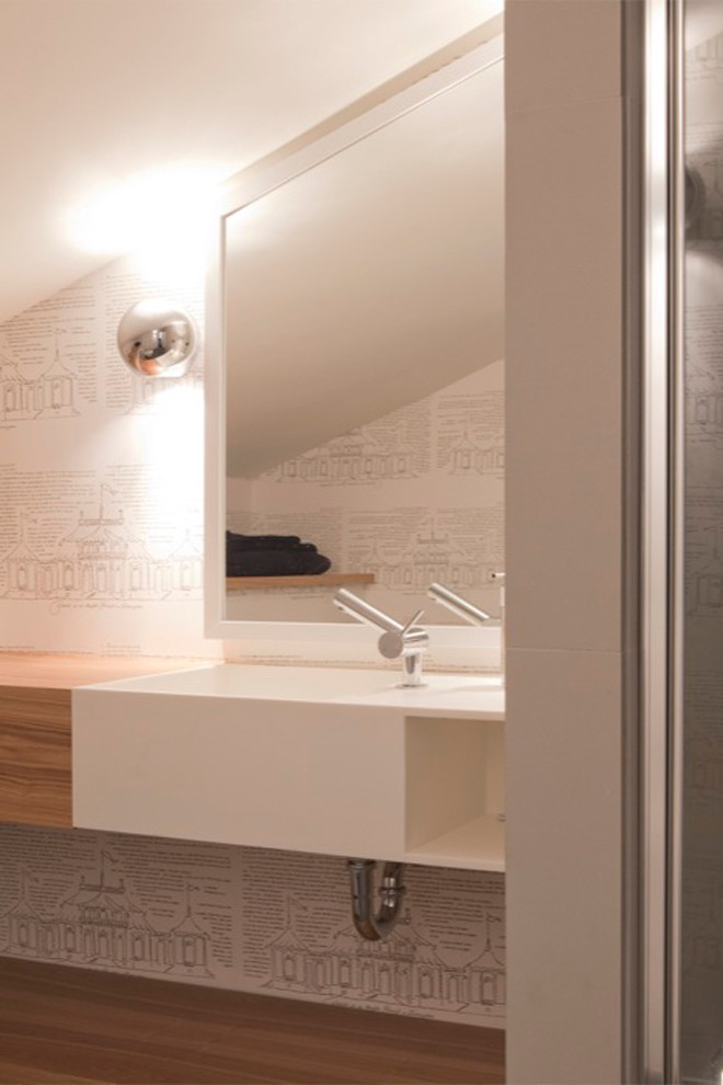 Modern inredning av ett litet badrum med dusch, med öppna hyllor, skåp i mellenmörkt trä, träbänkskiva, ett integrerad handfat, vita väggar, en vägghängd toalettstol, laminatgolv och brunt golv