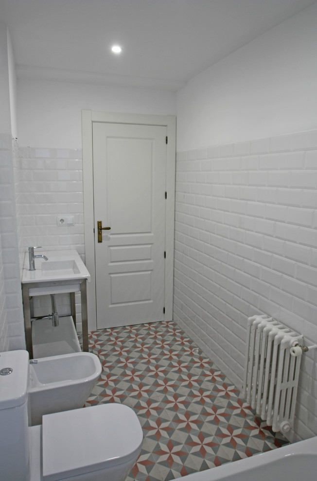 Inredning av ett nordiskt mellanstort en-suite badrum, med ett badkar i en alkov, en dusch/badkar-kombination, en bidé, vit kakel, keramikplattor, vita väggar, klinkergolv i keramik och ett konsol handfat