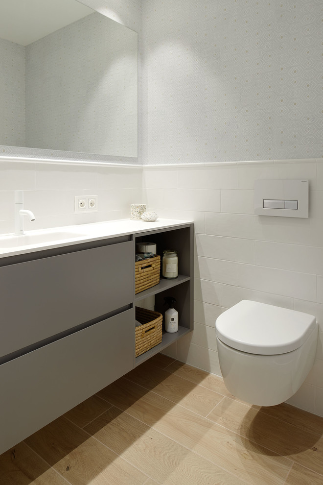 Photo of a medium sized modern ensuite bathroom in Other with freestanding cabinets, grey cabinets, a built-in shower, a wall mounted toilet, brown tiles, ceramic tiles, white walls, porcelain flooring, an integrated sink, engineered stone worktops, beige floors, a sliding door and white worktops.