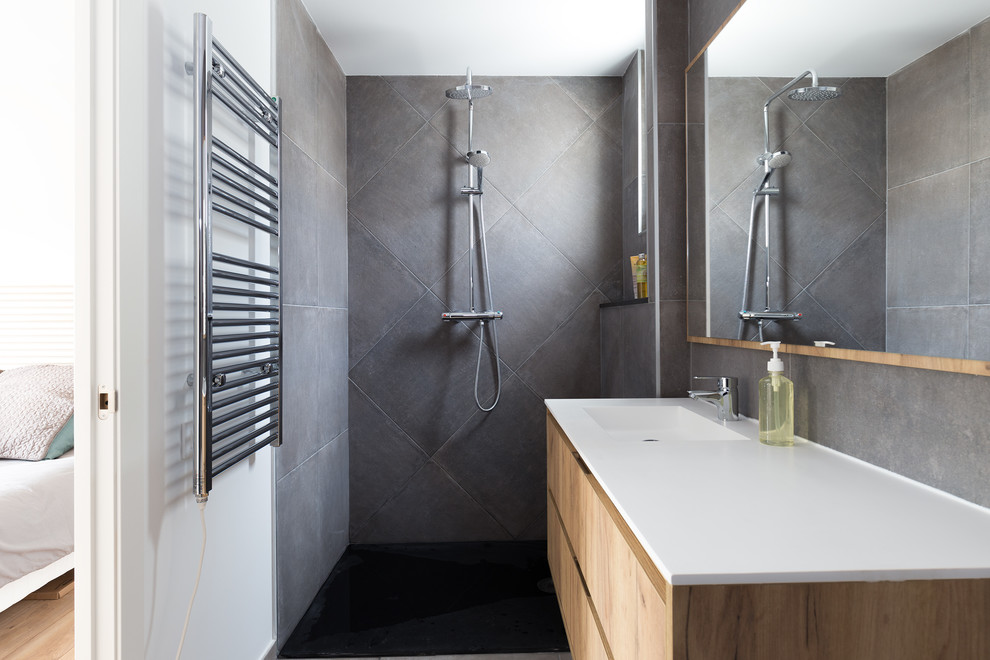 На фото: ванная комната в современном стиле с плоскими фасадами, светлыми деревянными фасадами, душем без бортиков, серой плиткой, белыми стенами, монолитной раковиной, серым полом, открытым душем и белой столешницей