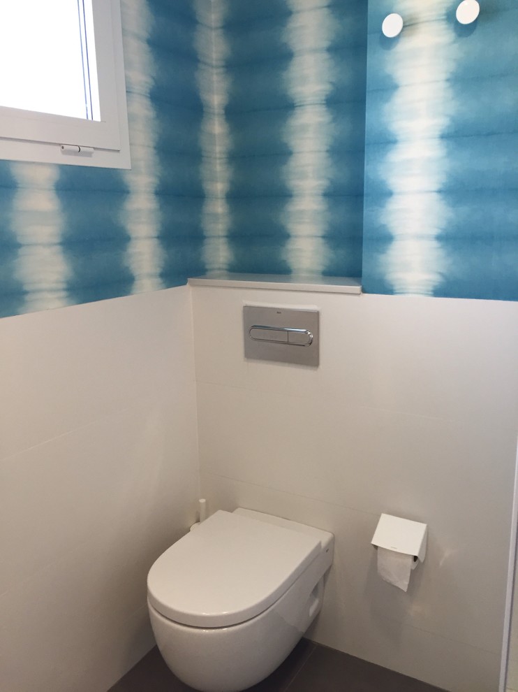 Пример оригинального дизайна: маленький туалет в стиле модернизм с плоскими фасадами, белыми фасадами, белой плиткой, керамической плиткой, унитазом-моноблоком, синими стенами, полом из керамической плитки, монолитной раковиной и серым полом для на участке и в саду