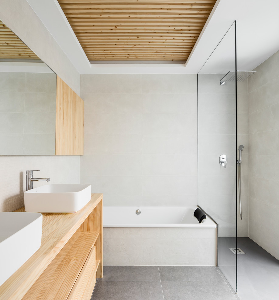 This is an example of a modern bathroom in Valencia with open cabinets, grey tiles, beige tiles, light wood cabinets, a built-in bath, a built-in shower, mosaic tiles, white walls, a vessel sink, wooden worktops, grey floors, an open shower and beige worktops.