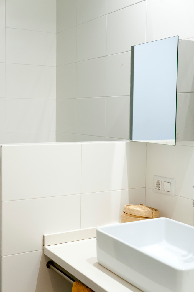 Inredning av ett modernt litet badrum med dusch, med en hörndusch, en vägghängd toalettstol, vit kakel, cementgolv, ett fristående handfat, grått golv och dusch med duschdraperi