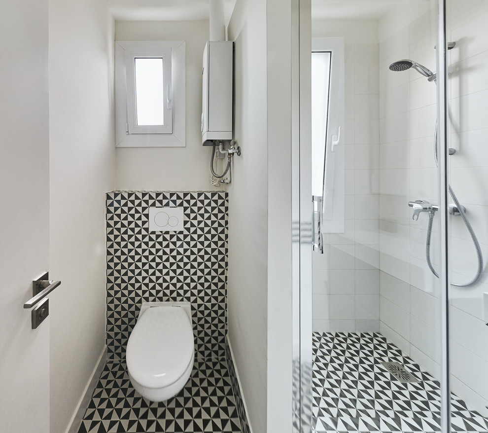 Idéer för små funkis badrum med dusch, med en kantlös dusch, en vägghängd toalettstol, svart och vit kakel, keramikplattor, vita väggar, klinkergolv i keramik och ett väggmonterat handfat