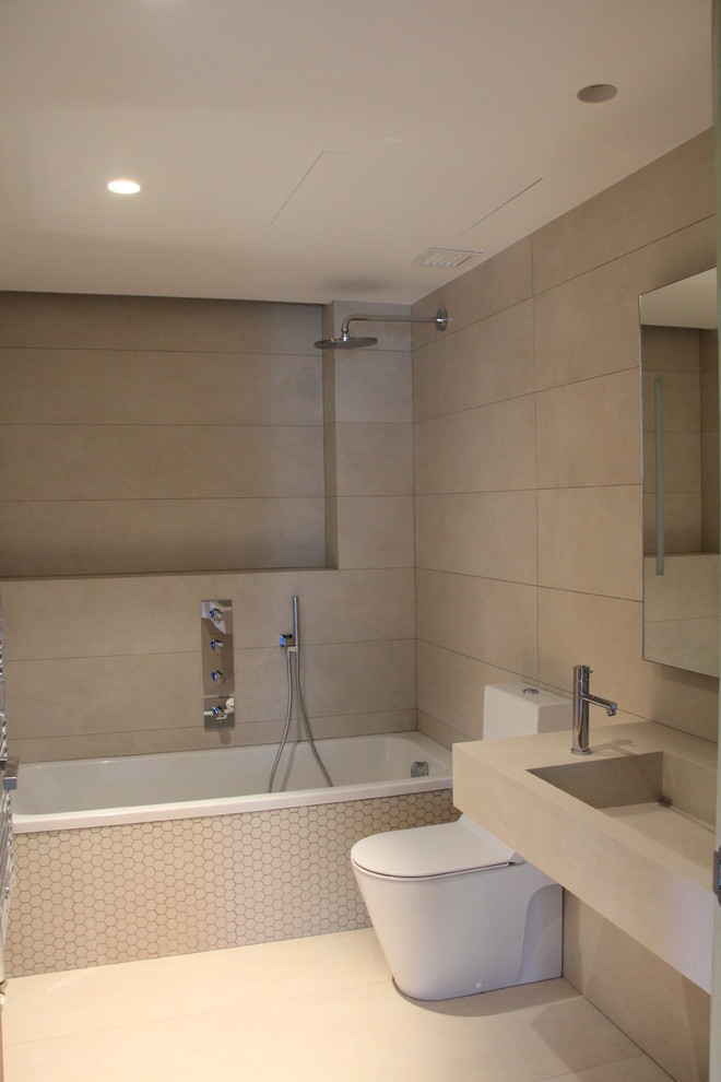 Foto de cuarto de baño principal actual de tamaño medio con bañera empotrada, combinación de ducha y bañera, sanitario de dos piezas, paredes beige y lavabo integrado