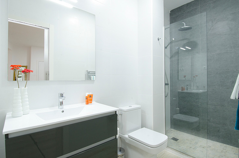 Imagen de cuarto de baño contemporáneo pequeño con armarios con paneles lisos, ducha a ras de suelo, sanitario de dos piezas, paredes blancas, aseo y ducha y lavabo integrado