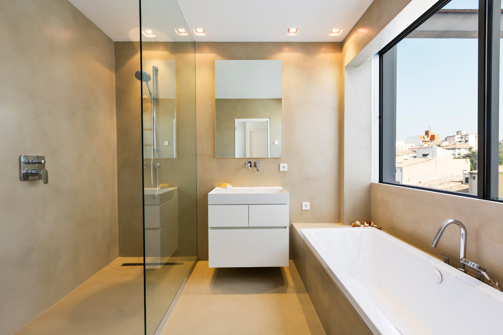 Modern inredning av ett mellanstort en-suite badrum, med släta luckor, vita skåp, ett platsbyggt badkar, en kantlös dusch, beige väggar, betonggolv och ett väggmonterat handfat