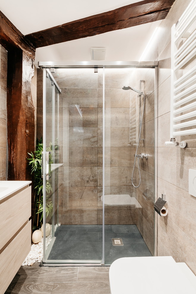 Inredning av ett modernt vit vitt badrum med dusch, med en kantlös dusch, beige kakel, dusch med skjutdörr, släta luckor, skåp i ljust trä, en vägghängd toalettstol, beige väggar, ett integrerad handfat och beiget golv