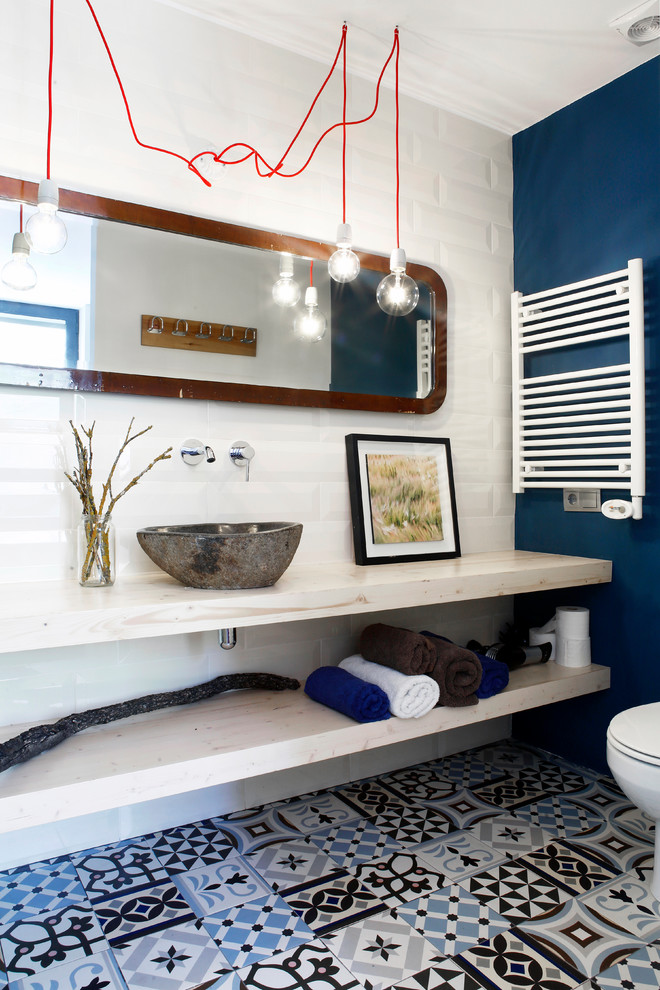 Aménagement d'une salle de bain éclectique en bois clair avec un placard sans porte, un plan de toilette en bois, un carrelage blanc, un carrelage métro, un mur bleu, carreaux de ciment au sol, une vasque, un sol multicolore et un plan de toilette beige.