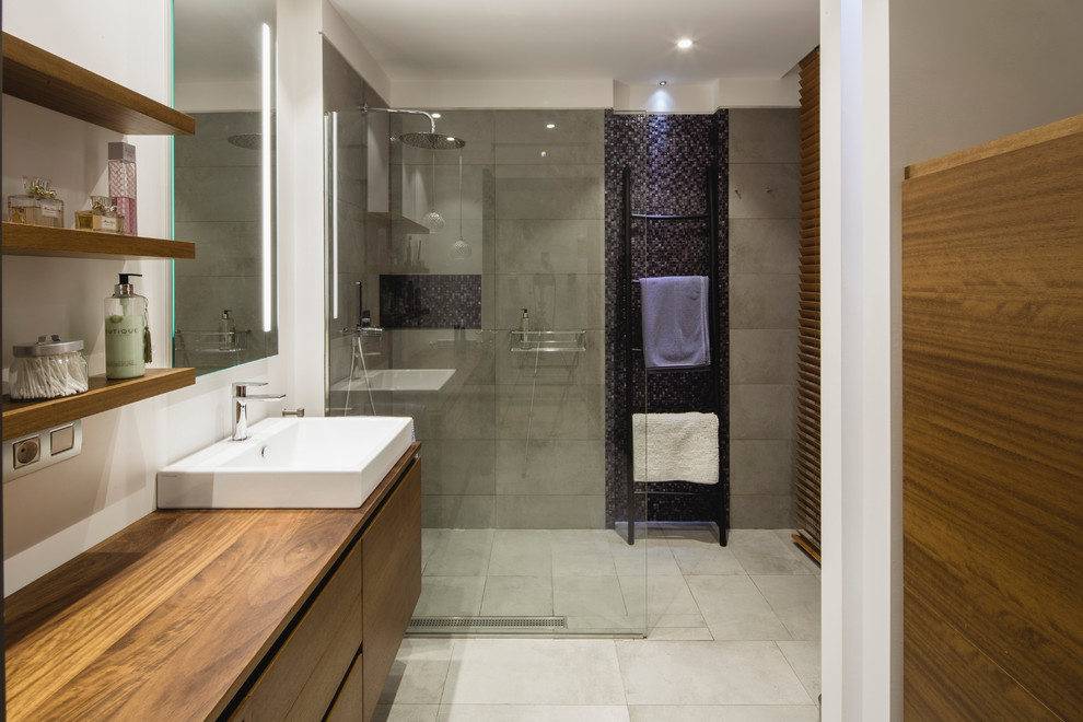 Bild på ett mellanstort funkis badrum med dusch, med släta luckor, skåp i mörkt trä, en kantlös dusch, vita väggar, klinkergolv i keramik, ett fristående handfat och träbänkskiva