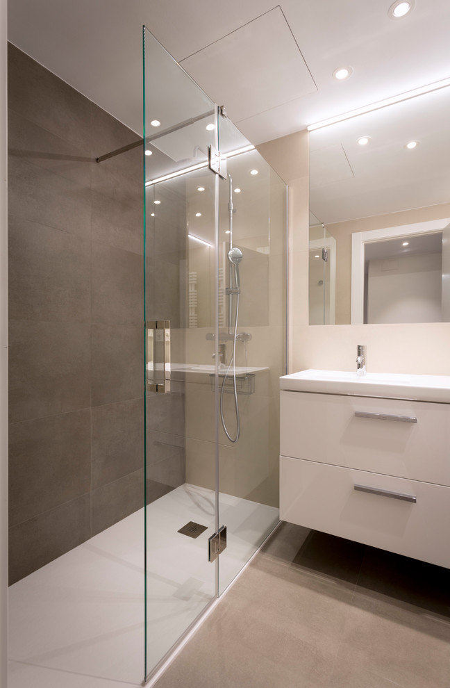 Idéer för ett mellanstort modernt beige badrum med dusch, med vita skåp, en kantlös dusch, beige kakel, ett avlångt handfat och dusch med gångjärnsdörr