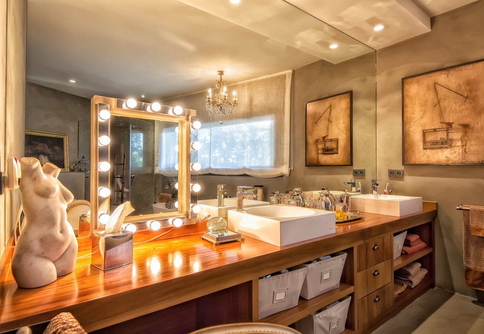 Идея дизайна: большая главная ванная комната в классическом стиле с плоскими фасадами, фасадами цвета дерева среднего тона, серыми стенами, бетонным полом, настольной раковиной, столешницей из дерева, отдельно стоящей ванной и душем над ванной