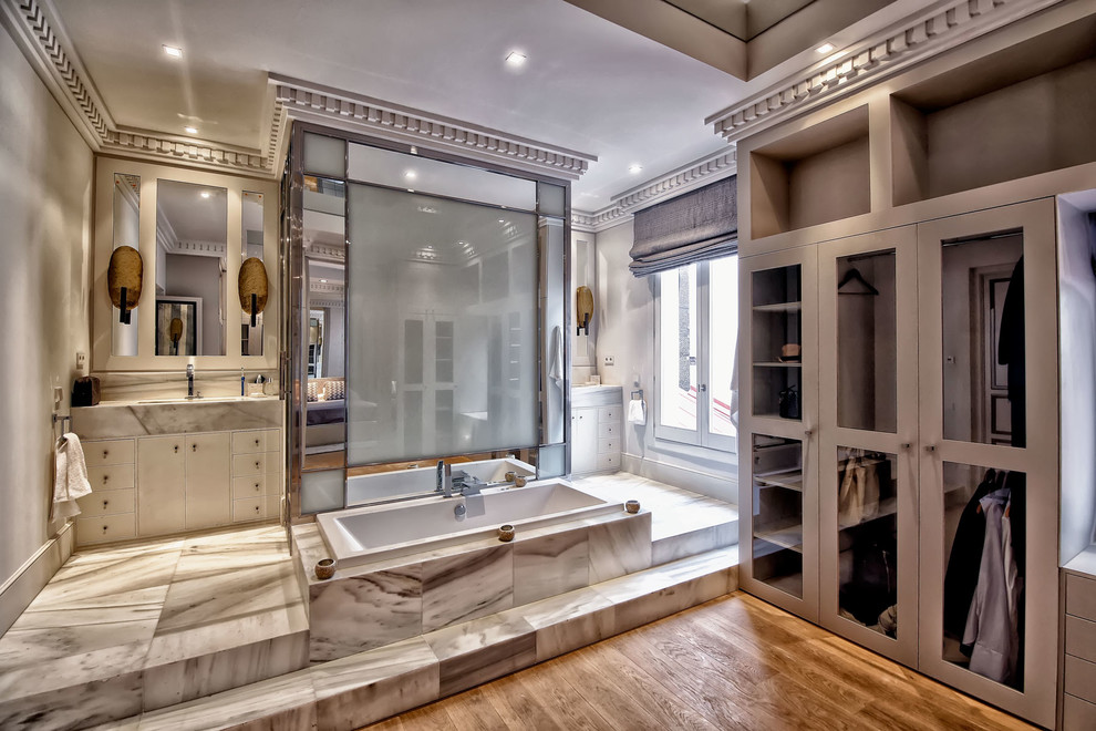 Inspiration for a medium sized traditional ensuite bathroom in Madrid with flat-panel cabinets, white cabinets, a built-in bath, grey tiles, stone tiles, grey walls, marble flooring, marble worktops, a shower/bath combination and a built-in sink.