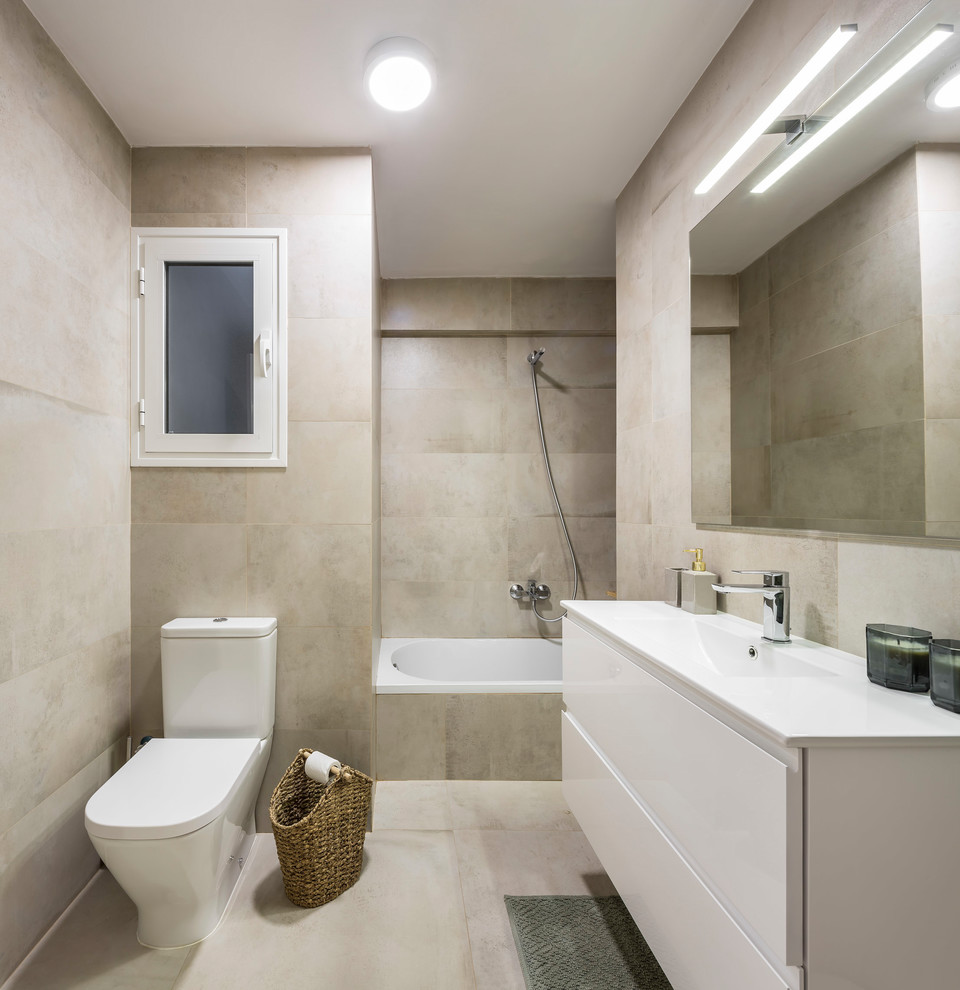 Exemple d'une salle de bain principale méditerranéenne avec des portes de placard blanches, WC à poser, un carrelage beige, un plan de toilette blanc, un placard à porte plane, une baignoire posée, un combiné douche/baignoire, un mur beige, un lavabo intégré et un sol beige.