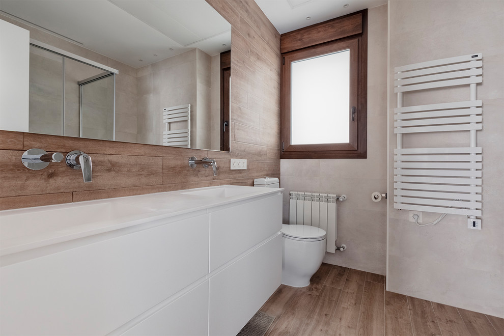 Medium sized contemporary shower room bathroom in Other with flat-panel cabinets, white cabinets, a built-in shower, a one-piece toilet, white tiles, ceramic tiles, multi-coloured walls, laminate floors, an integrated sink, brown floors, a sliding door and white worktops.