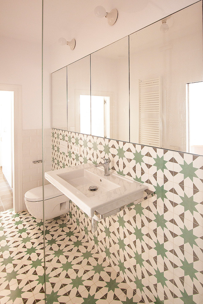 Exempel på ett mellanstort modernt badrum för barn, med öppna hyllor, vita skåp, en kantlös dusch, en vägghängd toalettstol, grön kakel, cementkakel, flerfärgade väggar, cementgolv, ett väggmonterat handfat och flerfärgat golv