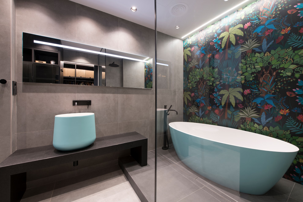 Inspiration for an expansive industrial ensuite bathroom in Other with open cabinets, turquoise cabinets, a freestanding bath, a built-in shower, a wall mounted toilet, grey tiles, porcelain tiles, grey walls, porcelain flooring, a vessel sink, black worktops, an enclosed toilet, a single sink, a floating vanity unit and grey floors.