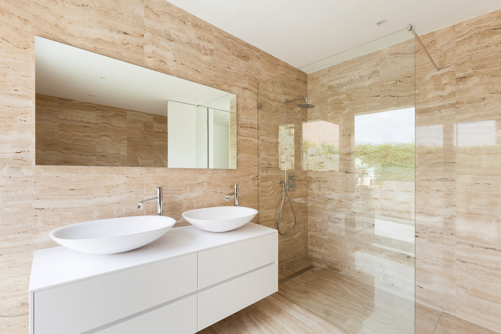 Bathroom - large contemporary master beige tile and marble tile marble floor and beige floor bathroom idea in Malaga with flat-panel cabinets, white cabinets, solid surface countertops, white countertops, a wall-mount toilet, beige walls and a vessel sink
