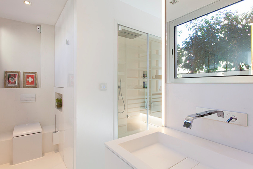 Mittelgroße Moderne Sauna mit offenen Schränken, weißen Schränken, bodengleicher Dusche, Toilette mit Aufsatzspülkasten, weißen Fliesen, weißer Wandfarbe, Betonboden, Trogwaschbecken, weißem Boden, Falttür-Duschabtrennung und weißer Waschtischplatte in Barcelona