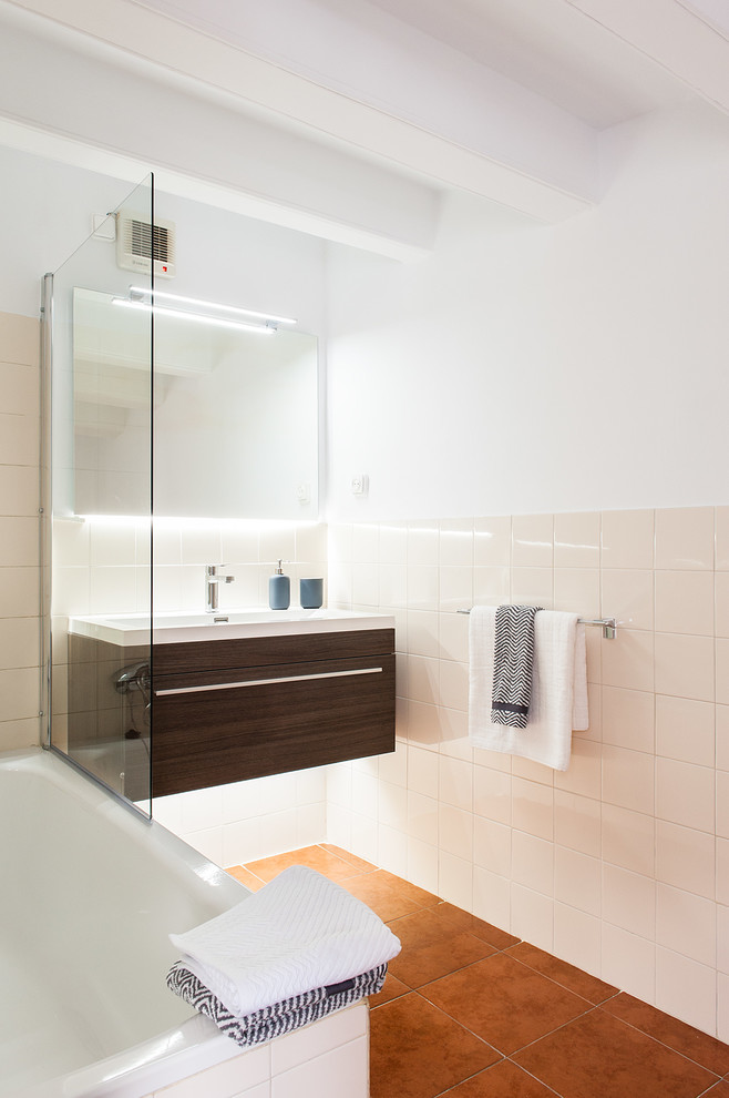 Imagen de cuarto de baño principal contemporáneo de tamaño medio con puertas de armario de madera en tonos medios, bañera encastrada, suelo de baldosas de cerámica y lavabo suspendido