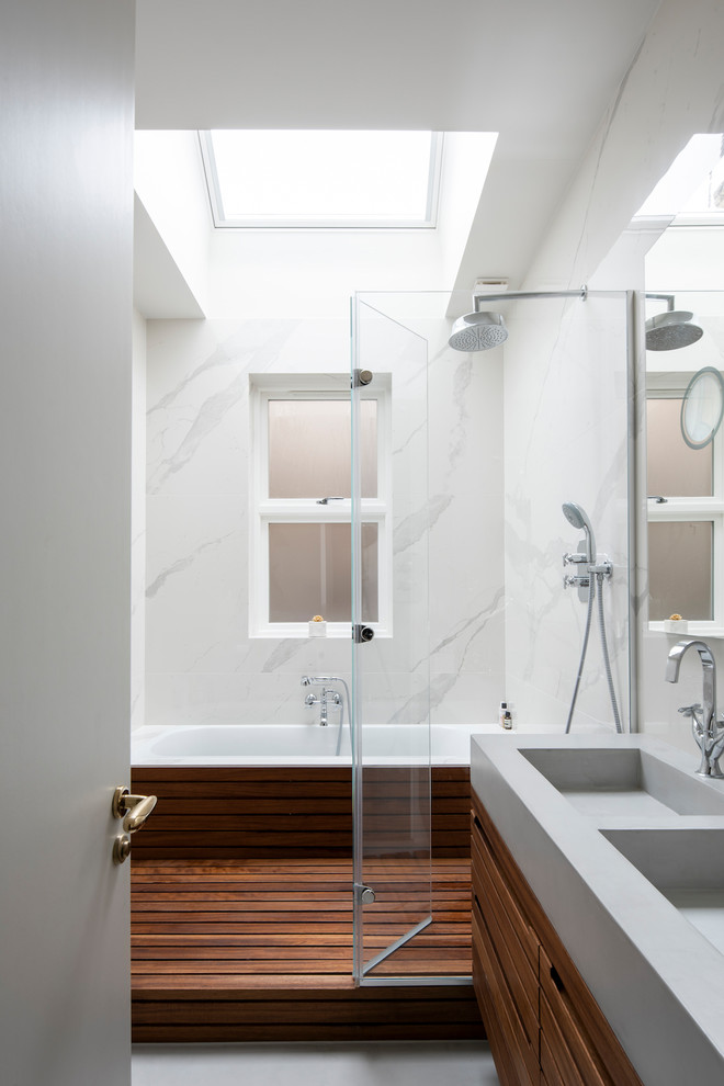 Inspiration for a small modern 3/4 white tile and marble tile concrete floor and gray floor bathroom remodel in London with furniture-like cabinets, medium tone wood cabinets, a wall-mount toilet, white walls, a wall-mount sink, marble countertops, a hinged shower door and gray countertops