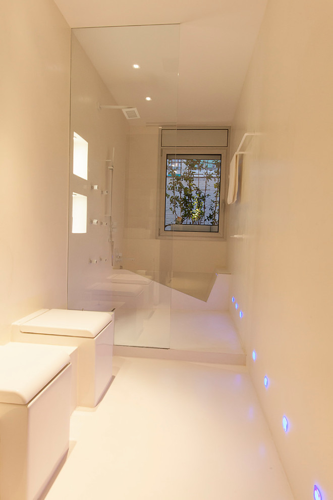 バルセロナにある広いコンテンポラリースタイルのおしゃれなマスターバスルーム (オープンシェルフ、白いキャビネット、和式浴槽、オープン型シャワー、一体型トイレ	、白いタイル、白い壁、コンクリートの床、横長型シンク、白い床、オープンシャワー、白い洗面カウンター) の写真