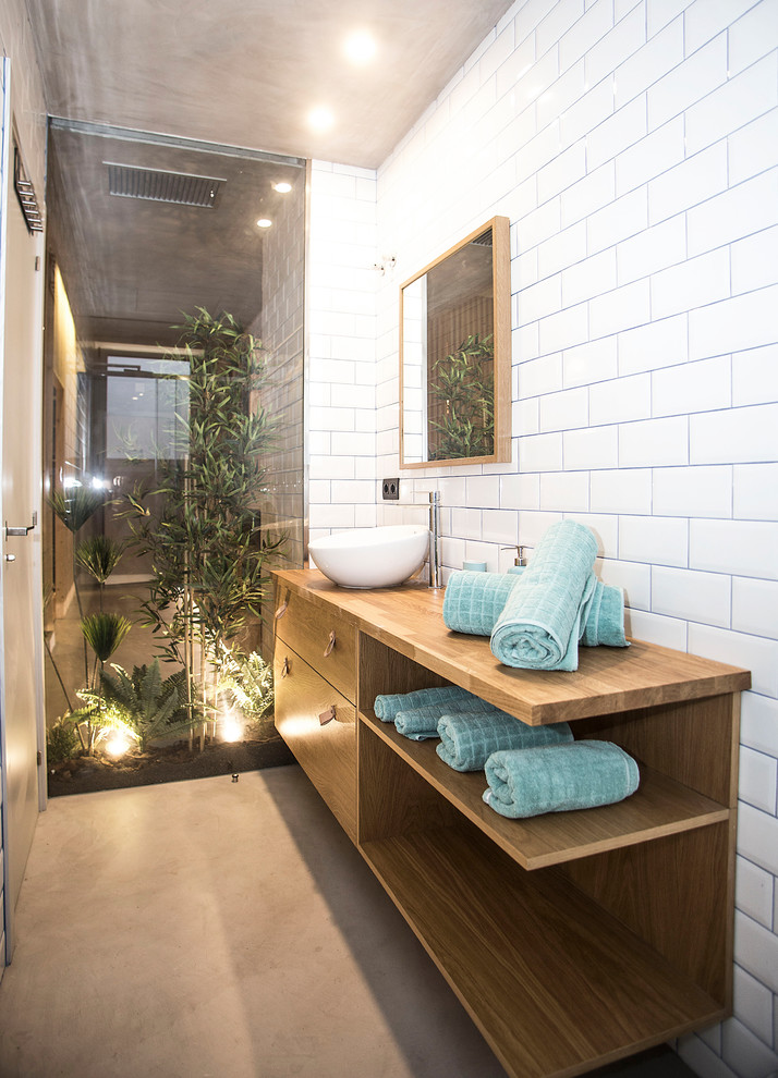 Cette image montre une petite salle d'eau urbaine avec un espace douche bain, un carrelage blanc, un mur blanc, une vasque, un sol gris, une cabine de douche à porte battante et sol en béton ciré.