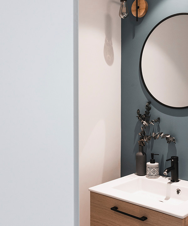 Modelo de cuarto de baño escandinavo pequeño con puertas de armario de madera clara, paredes azules, suelo de madera clara, lavabo con pedestal, encimera de cuarzo compacto y encimeras blancas