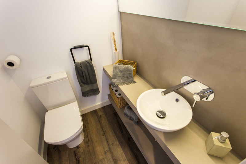 Imagen de cuarto de baño flotante actual pequeño con puertas de armario blancas, suelo de madera en tonos medios y microcemento