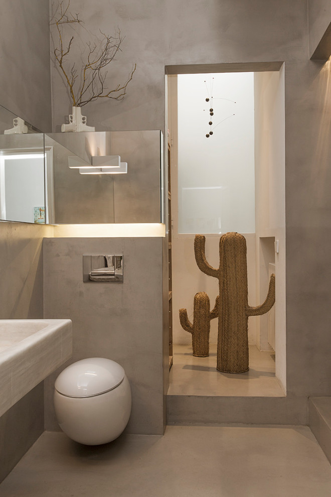 На фото: главная ванная комната среднего размера в современном стиле с отдельно стоящей ванной, серой плиткой, белыми стенами, бетонным полом, подвесной раковиной, мраморной столешницей и серым полом с