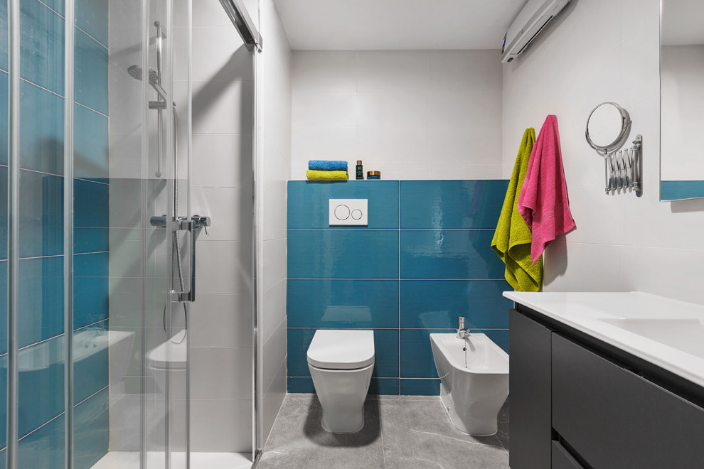 Photo of a small contemporary ensuite bathroom in Alicante-Costa Blanca with flat-panel cabinets, white cabinets, a built-in shower, a bidet, blue tiles, ceramic tiles, white walls, cement flooring, an integrated sink, grey floors, a sliding door, an enclosed toilet and a built in vanity unit.