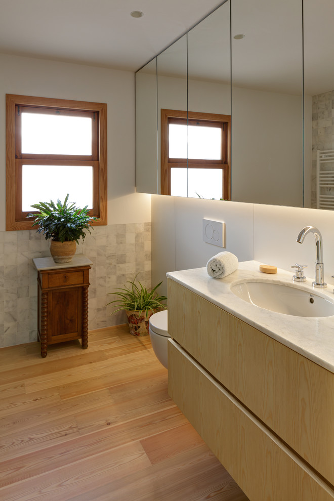 Imagen de cuarto de baño contemporáneo sin sin inodoro con bidé, baldosas y/o azulejos de mármol, paredes blancas, suelo de madera clara, encimera de mármol y ducha con puerta con bisagras