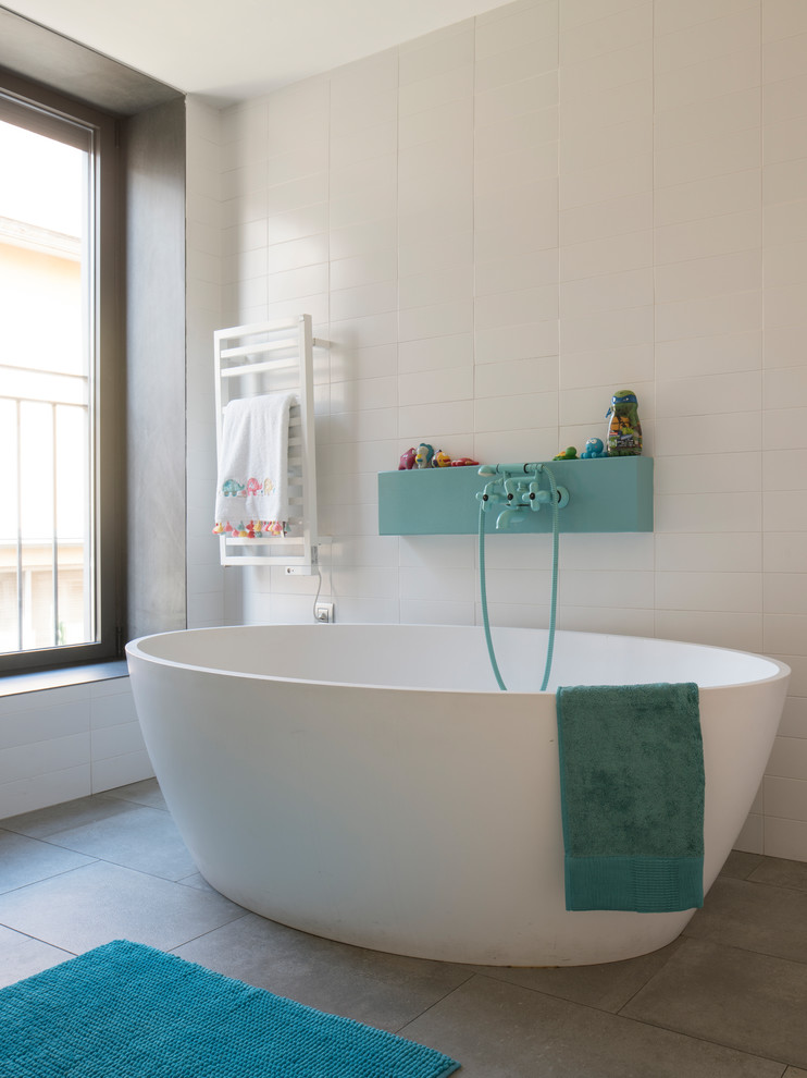 Inspiration for a large eclectic family bathroom in Barcelona with freestanding cabinets, white cabinets, a freestanding bath, a one-piece toilet, grey tiles, ceramic tiles, white walls, ceramic flooring, a wall-mounted sink, solid surface worktops, grey floors, an open shower and white worktops.