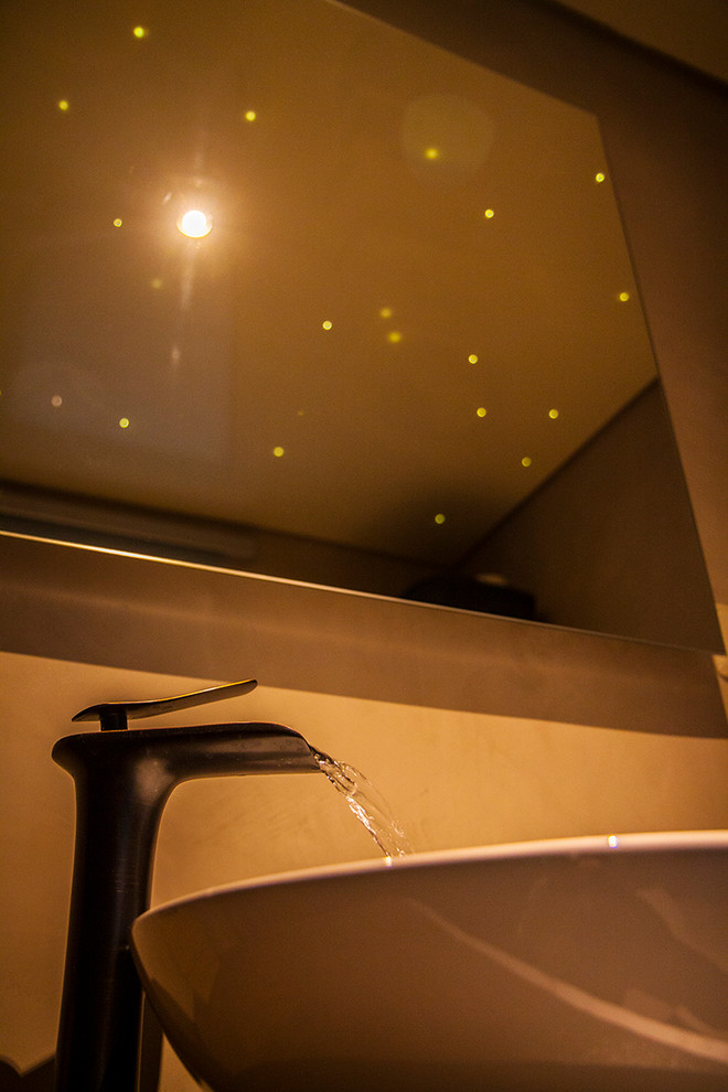 Réalisation d'une petite salle de bain principale design avec des portes de placard marrons, un espace douche bain, WC à poser, un carrelage beige, un mur beige, sol en béton ciré, une vasque, un sol beige et un plan de toilette beige.
