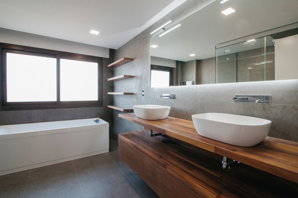 Idéer för att renovera ett stort funkis en-suite badrum, med släta luckor, skåp i mellenmörkt trä, ett badkar i en alkov, en dusch/badkar-kombination, ett fristående handfat och träbänkskiva