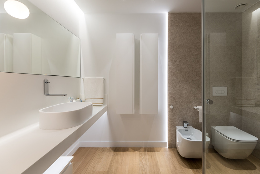 Inspiration for a medium sized scandinavian ensuite bathroom in Alicante-Costa Blanca with white cabinets, an alcove shower, a wall mounted toilet, brown tiles, ceramic tiles, white walls, light hardwood flooring, a vessel sink, quartz worktops, a sliding door, white worktops, an enclosed toilet and a single sink.